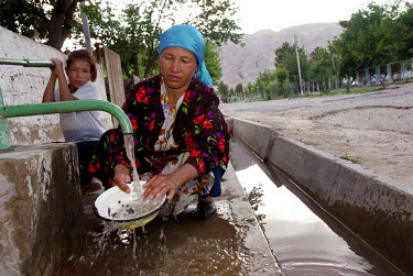 A woman washing dishes in an irrigation canal. 43% of the population of Tajikistan has no access to piped water, with nearly 25% using rivers, irrigation ditches and pools as their main sources of dri...