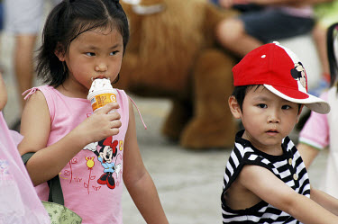 Children in Disney branded clothes eating ice cream on a family outing to an air show at a military base near Taipei.