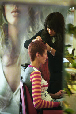 A woman having hair extensions added in a hairdressing salon. The cost can be as much as 1500 euros for a full head of hair.