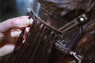 A woman having hair extensions added in a hairdressing salon. The cost can be as much as 1500 euros for a full head of hair.