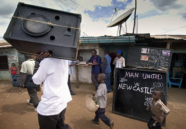 In Kibera, one of the biggest slums in Africa, a billboard advertises the English football match between Manchester United and Newcastle United, shown live on satellite television.