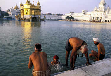 Sikh worshippers bathing in the pond surrounding the Golden Temple. Also known as Harmandir Sahib, the temple is the sacred home of the Sikh faith.