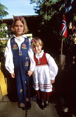 Nine and five year old sisters dressed in their national costume and with the Norwegian flag.