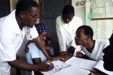 A medical staff of four discuss the outbreak of measles in their district in front of one of their patients.