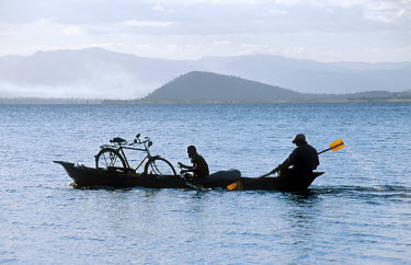 Two men transporting a bicycle across Lake Chicamba by boat.
