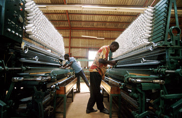 Men operating thread spinning machinery in a factory producing fishing nets.