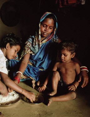 Janaki Mallick, 9 months pregnant, cooks for and feeds her children. In this village there is a trained traditional birth attendant who has delivered over 100 babies and claims never to have lost a ba...