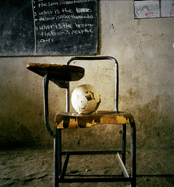 'Where is the ball? The ball is on the chair' A classroom in Chimbiri school.~Children take turns in putting objects on the chair, while the teacher writes on the blackboard. The teachers learn Englis...