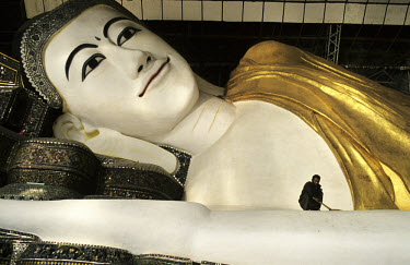 The reclining Shwethalyaung Buddha, measuring 55 meters long and 16 meters high, is cleaned by an employee.