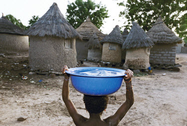 Woman carrying water home on her head. The women collect 20 litres of water at a time, which weighs 20kg.