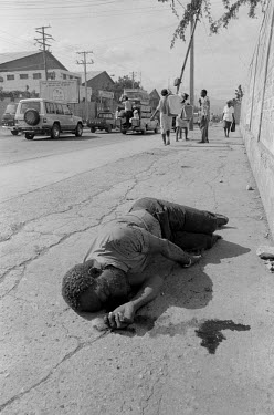 An executed man lies in the street covered in flies. He was shot through the back of the neck in a style reminiscent of the right wing FRAPH (Front pour l'Avancement et le Progres Haitian) indicating...