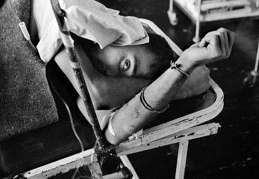 A wounded man with an intravenous drip in hospital during the siege on Sarajevo by Serb troops.  Doctors and nurses working in the hospitals through the conflict operate on the injured without electri...