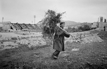 A man carries firewood through a field next to a cemetery during the siege on Sarajevo by Serb troops. Gas and electricity were cut off for long periods during the 4-year siege, in which over 10,000 p...