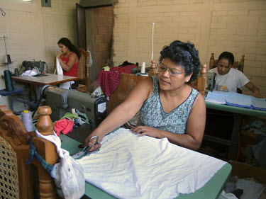 Women make clothes from recycled materials using sewing machines in a workshop.