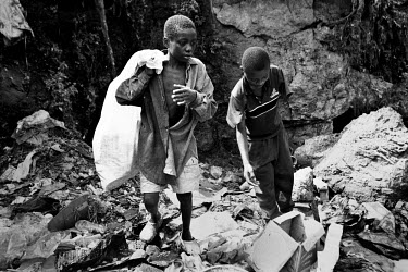 Siah (right) and Mohammed scavenge a city dump for plastic they can sell for recycling. Siah's arm was amputated by rebel militia during the civil war and now lives on the streets. Thousands of innoce...