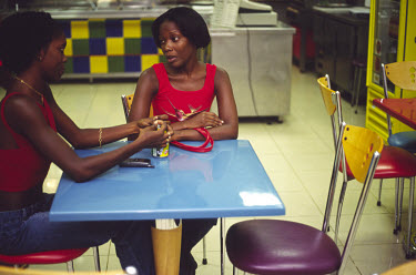 Two middle class girls sit in a fast-food restaurant in a shopping centre in Luanda.