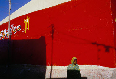 A woman walks past a painted wall advertising cigarettes in a street in the centre of the city.