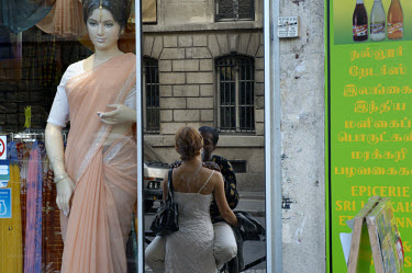 Mixed race couple kissing, reflected in mirror next to an Indian sari shop on Faubourg St Denis in the 18th arrondissement.