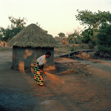 A woman with a print of brooms on her dress sweeps the cleared ground around her house early in the morning.    The village of Dickson contains 55 households and some 300 inhabitants. In 2005 photogra...