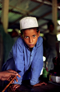 A young student at the Madrassah (Madrasa), an Islamic religious school where separate classes of boys and girls are taught the Koran.  Madrassahs in Bangladesh are often attached to mosques and form...