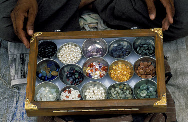 Vendor displaying pearls and other precious stones for sale at a daily gem market at the Johari Bazaar.