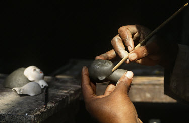 A potter carves a face from clay in the Kurmatuli district, an area where pottery workshops are dedicated to producing religious icons.