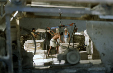 Labourers work in a recycling factory, where paper is made into sheets of cardboard.