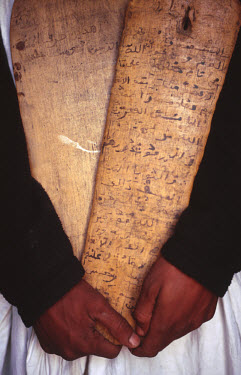 A young librarian in an ancient library holds two 'lahs', wooden tablets inscribed with verses from the Koran or Hadith (Haddith), which contain sayings by the Prophet Muhammad and his companions.  Th...