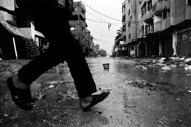 A pedestrian hurries through the street in an area destroyed by conflict.