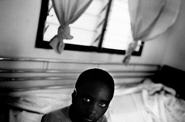 A young boy sits on the edge of a bed in the German-run Disability Hospital CCBRT (Comprehensive Community Based Rehabilitation Tanzania).  Patients here have to return to the hospital many times, whi...