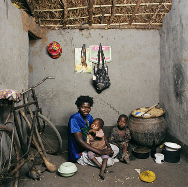 Livinese Henry (27) with her children Simenti (6) and Owen (2) and their pet rabbit, in her house where she keeps their bicycle in fear of thieves.