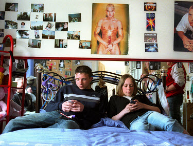 Lauren and Gary send text messages on their mobile phones as they sit on Lorianne's bed in her bedroom.  'All Dressed up' is a series exploring how various groups of teenagers socialise and the places...