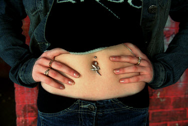 A teenager displays her belly button piercing and jewellery.  'All Dressed up' is a series exploring how various groups of teenage girls socialise and the places which are special to them.  Having sha...