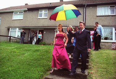 Girls leave the house under an umbrella on their way to the  prom.  The prom is an important event in the school calendar for school leavers, who enjoy one of their last nights together as secondary s...
