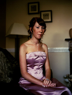 Claire (15) waits in the lounge at home for the limousine to pick her up and take her to the school prom.  She wears a pink ball dress which she found after trying on more than 10 others.  The prom is...