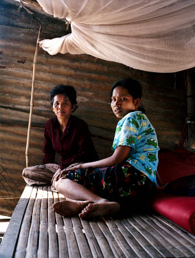 Pov and her mother sit at home.  Pov, who is HIV positive, managed to escape the  brothel to which she had been sold at the age of 14.