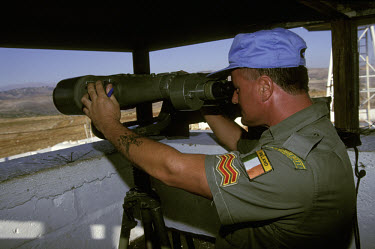 Soldier from the Irish battalion of the peacekeeping force for the United Nations Interim Force In Lebanon (UNIFIL) looks through a pair of binoculars from a lookout post towards the Israeli border in...