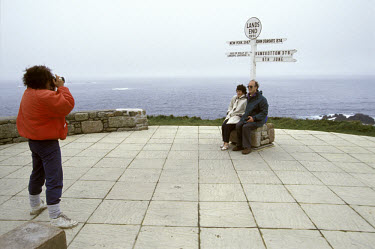 Visitors pose for a photograph under a signpost at Britain's sounthernmost point, which is a popular tourist attraction.