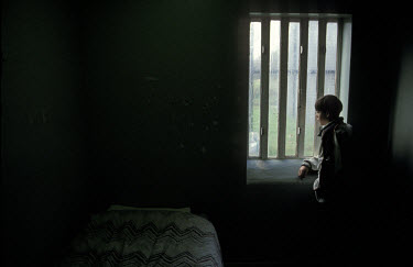 A juvenile offender looks out of the window in a secure youth detention centre.