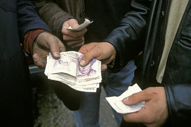 Cash in the form of twenty pound notes is exchanged at a second hand car lot in the East End of the city.