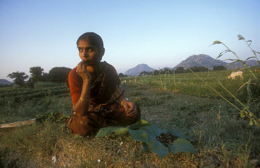 Woman taking a break from harvesting groundnuts in a field.
