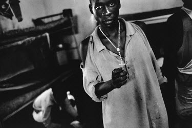A young man in Gitarama Prison, held on charges of genocide, clutches a crucifix.
