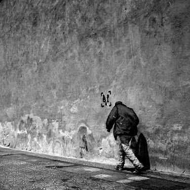 Man walking uphill next to a wall.