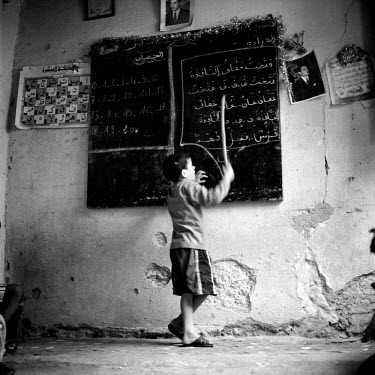 A boy reads a verse from the blackboard at a Madrassah (Madrasa) a Koranic school.