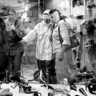 Shoppers look in the window of a shoe shop.
