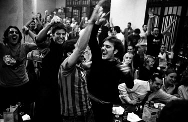 FC Barcelona supporters watching in a bar celebrate a goal by Ronaldinho during a Champions League football match against AC Milan.