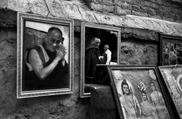 A Tibetan Buddhist monk and a Tibetan woman reflected in a mirror on sale alongside a framed picture of the Dalai Lama. About 300 monks live in Shechen monastery in Bodhath, from a total of around 20,...