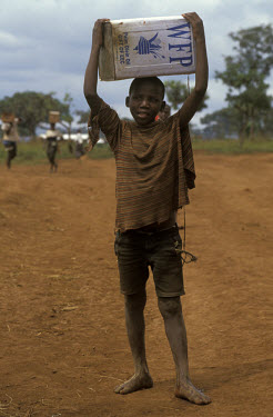Rwanda child at Benako refugee camp which shelters refugees fleeing the Rwandan genocide.  He carries a can of Palm oil provided by the World Food Programme (WFP).