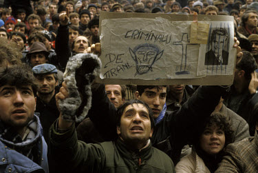 Protesters hold up a placard in defiance of the former leader of the Communist Party of Romania, Nicolae Ceausescu, labelling him a 'criminal'.