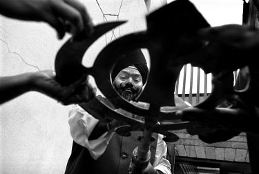 Cleaning a Khanda which sits atop the flagpole at the Ramgarhia Sikh temple.  The Khanda is an important Sikh symbol and is regularly taken down and cleaned as a mark of respect during festivals.